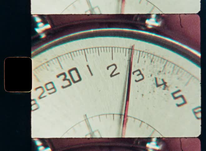 A macro shot of a vintage stopwatch's second hand ticking as seen on a retro film scan