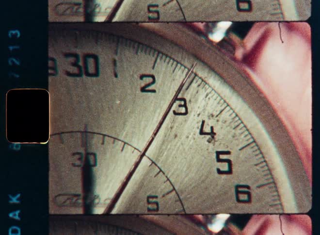 A macro shot of a vintage stopwatch's second hand ticking by, captured on old film