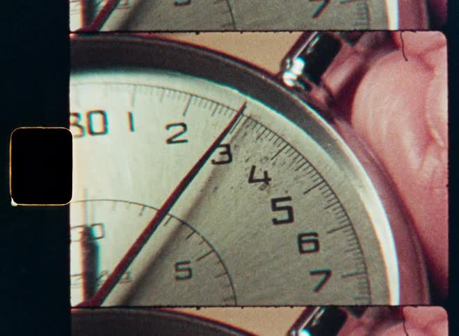 Close-up shot of a running stopwatch, captured with a vintage filmstrip effect, showing the seconds ticking away