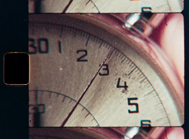 An extreme close-up film scan captures a vintage stopwatch as the second hand ticks by