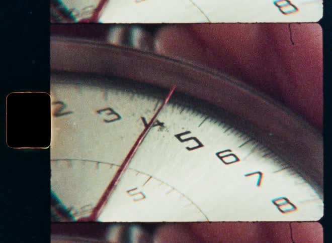 A gritty close-up shot on film of a vintage stopwatch as the second hand moves across the numbers