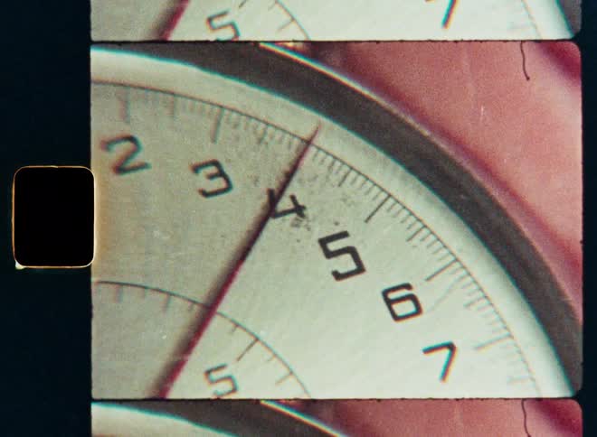 Vintage 8mm film shows a close-up of a stopwatch's second hand sweeping across the dial