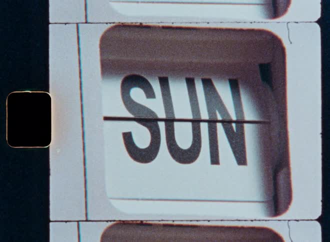 Days of the week quickly pass by on a vintage flip calendar in a grainy, retro film style