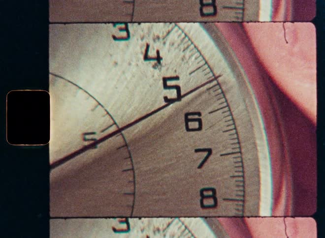 A vintage 8mm film strip scan shows a macro close-up of a ticking stopwatch as the camera pans across its face