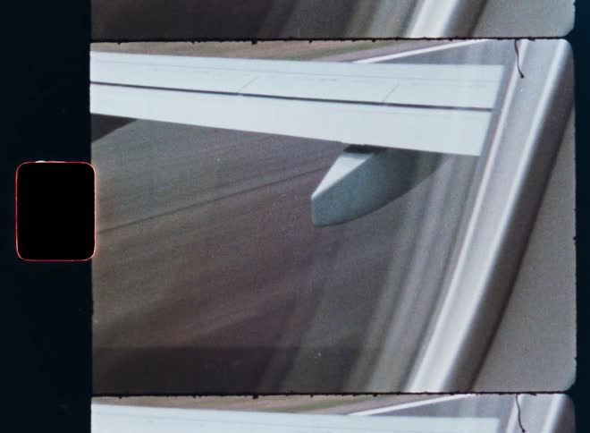 A vintage film scan shows the view from an airplane window as it speeds down the runway during takeoff