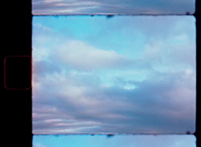 A dreamy vintage 8mm film scan of a pastel-colored cloudy sky, complete with film grain and frame lines
