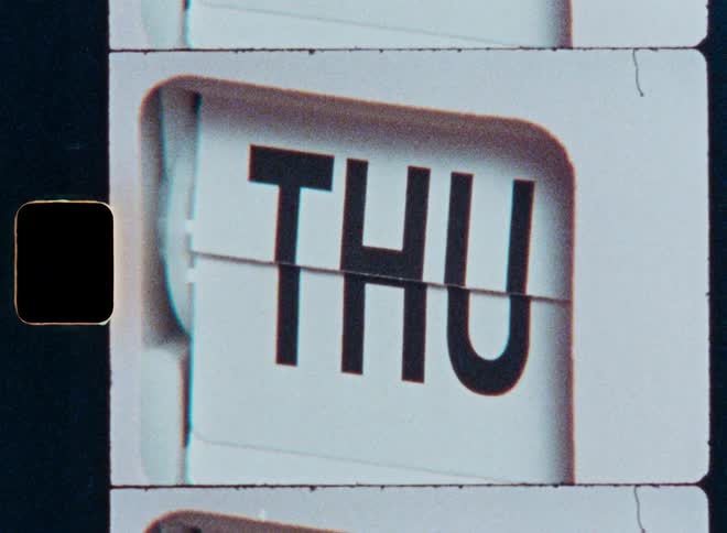 A vintage flip calendar clicks through the days of the week in a grainy Super 8mm film-style close-up