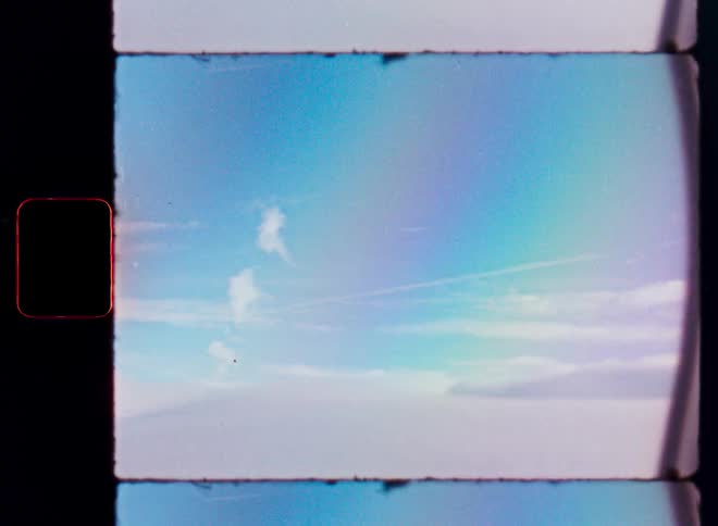 A dreamy, ethereal view from an airplane window above the clouds captured on vintage film with a rainbow effect