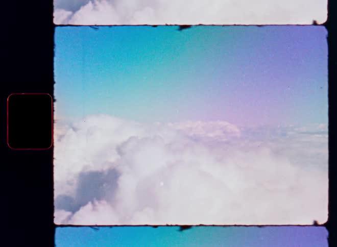 A dreamy vintage film shot of pastel-colored skies above a sea of fluffy white clouds, complete with film grain and a border