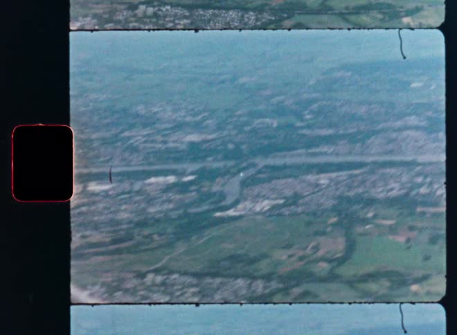 Vintage Super 8 film captures a shaky aerial view of a city with a winding river