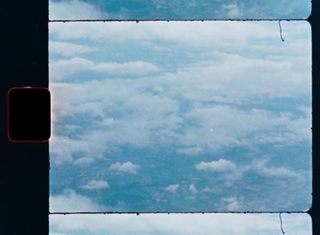 A dreamy, vintage Super 8 film view of white clouds drifting across a blue sky, framed by a film strip border