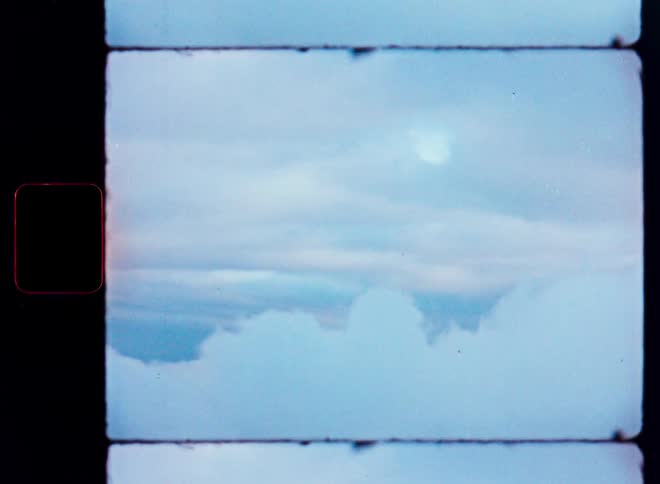 A dreamy, vintage film loop shows a serene view of soft clouds in a pale blue sky