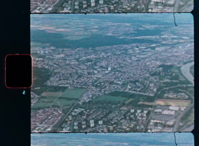 Vintage 8mm film shows an aerial view of a sprawling city and a winding river from an airplane window