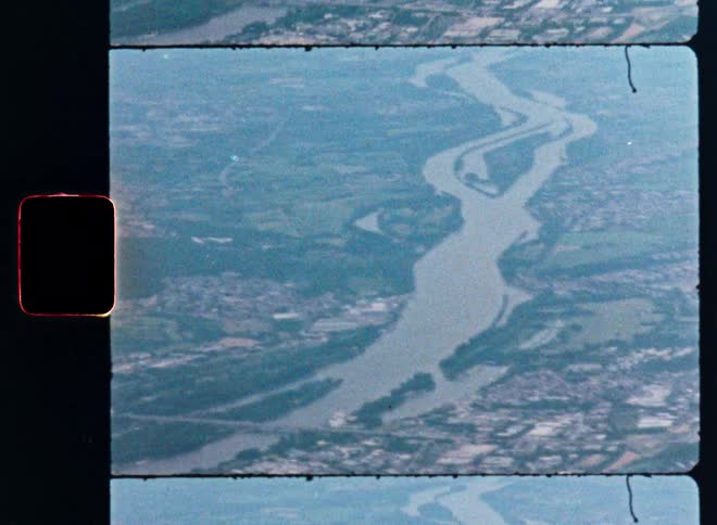 An aerial view from a vintage 8mm film shows a sprawling river weaving through a hazy European landscape