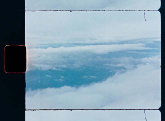 An aerial view of the sky and clouds as seen from an airplane window, captured on vintage film