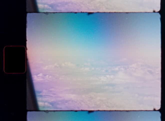 Vintage 8mm film captures an ethereal aerial view of the clouds with a beautiful rainbow light leak