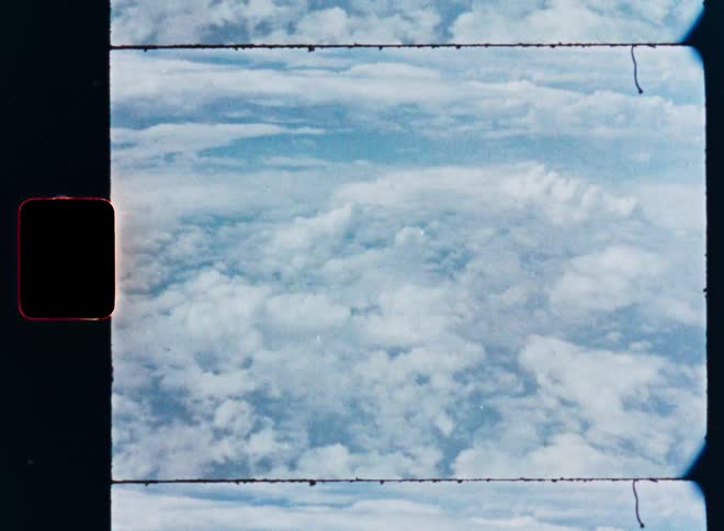 A vintage film scan captures a serene, high-altitude aerial view of a vast expanse of clouds against the blue sky