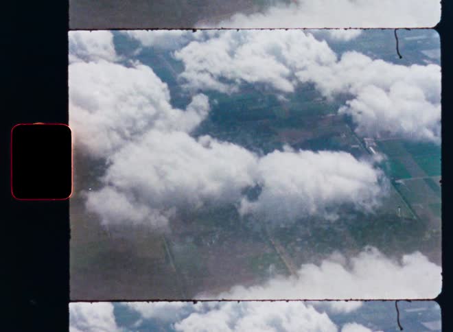 Archival 8mm film scan of a serene aerial view of clouds floating over a green landscape