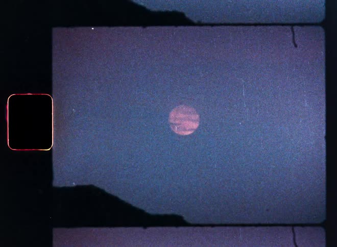 A mysterious pink celestial body hangs in a grainy, dark blue sky over a mountain silhouette in this Super 8 film animation