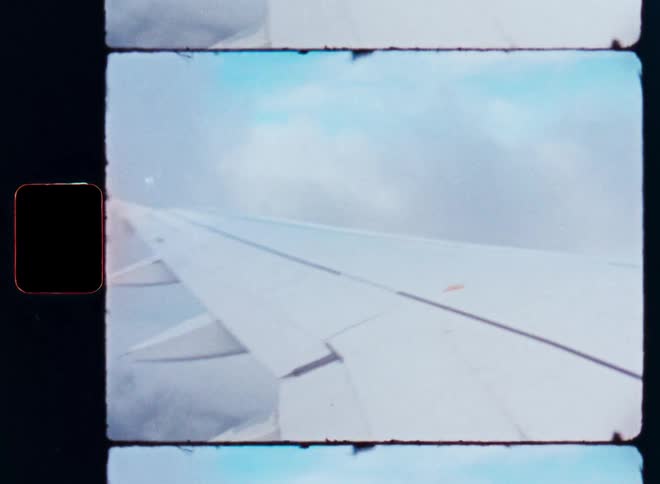 A dreamy vintage film shot of an airplane wing flying through the beautiful clouds