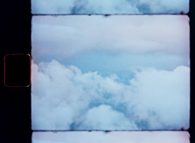 A dreamy, vintage film scan captures fluffy white clouds against a pale blue sky, complete with a film border and light leaks