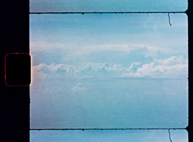 Vintage 16mm film scan of a dreamy blue sky with clouds stretching to the horizon