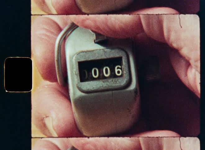 Close-up shot on vintage film of a hand clicking a mechanical counter from zero to ten