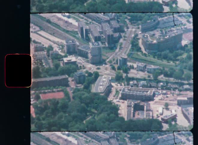 A vintage 8mm film scan shows a shaky, aerial view zooming out over a European city