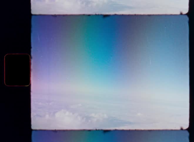 Dreamy Super 8mm footage shows an aerial view above a sea of clouds with a colorful rainbow light leak effect