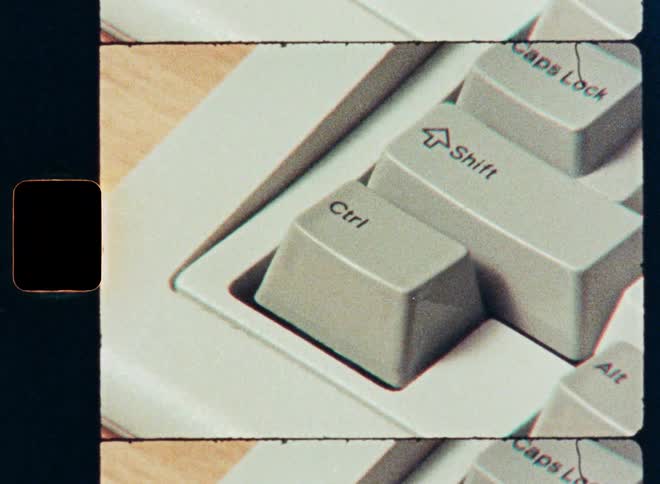 A close-up shot of a finger pressing the Control and Shift keys on a vintage computer keyboard with a retro film effect
