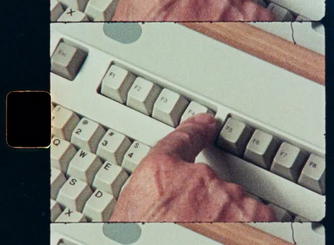 A close-up shot on Super 8 film of a finger pressing the Alt and F4 keys on a vintage computer keyboard