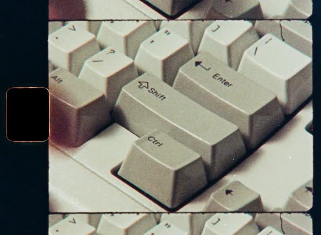 A finger presses the enter key on a vintage keyboard in a retro film strip close-up