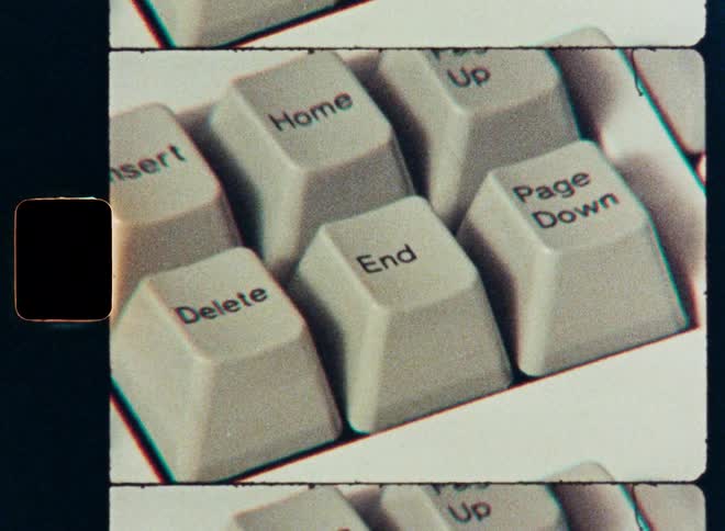 A grainy, close-up shot of a finger pressing the 'End' key on a vintage computer keyboard, framed like a classic film strip