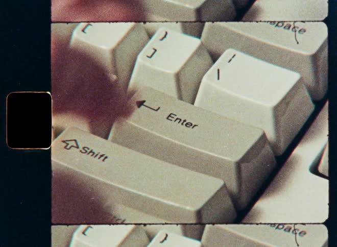 Close-up of a finger pressing the 'Enter' key on a retro computer keyboard, shot on vintage film with a film strip border