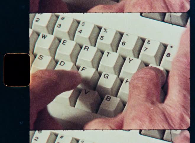 A close-up of a person typing on a vintage computer keyboard with a retro film aesthetic