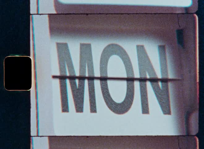 The days of the week flip by on a retro calendar, captured on grainy vintage film with sprocket holes