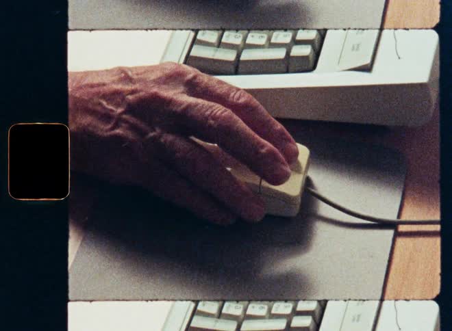 A close-up shot on 8mm film of a hand using a vintage computer mouse from the 1980s