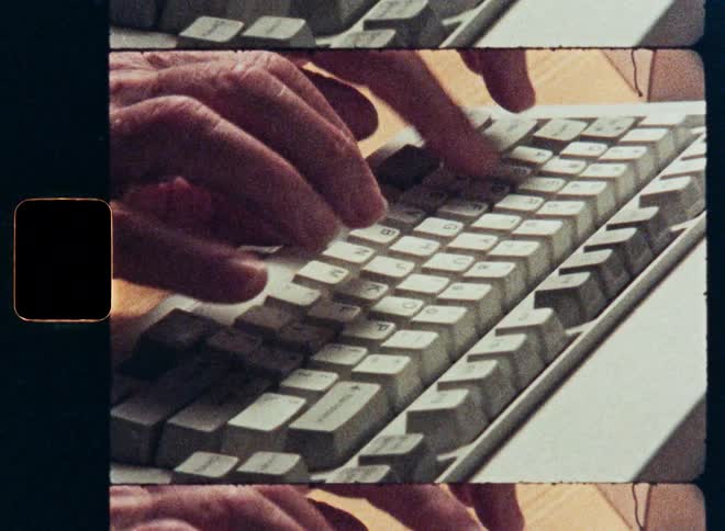 Close-up of hands typing on a vintage computer keyboard with a retro film aesthetic