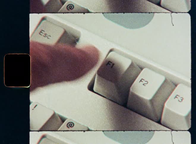 A retro film strip shows a close-up of a finger pressing the escape and function keys on an old computer keyboard