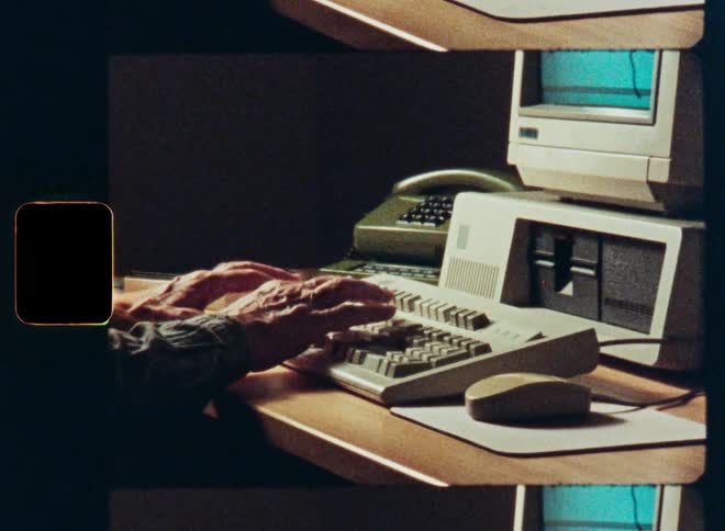 A person types and uses the mouse on a vintage 1980s desktop computer in this authentic film scan