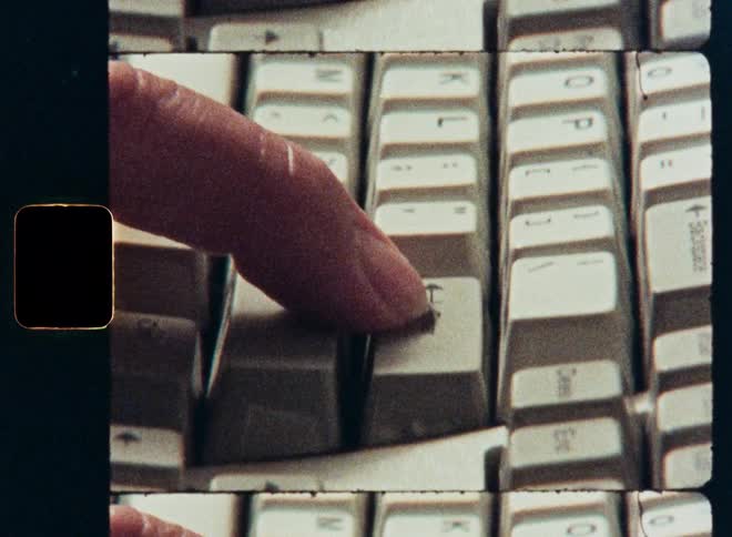 A retro film-style close-up of a finger typing on a vintage computer keyboard with a multi-frame effect