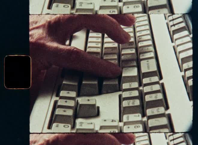 Vintage film shot of a person's hand typing on an old retro computer keyboard