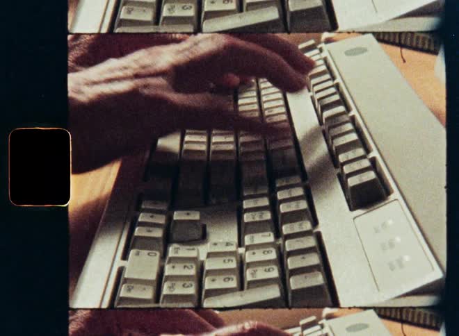 Archival super 8mm film of hands typing on a vintage 1980s computer keyboard and mouse