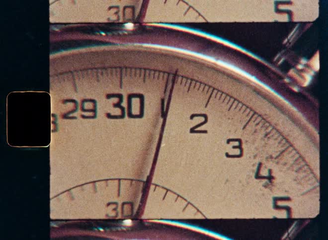 An extreme close-up of a vintage stopwatch counting seconds, captured with an old film gate effect