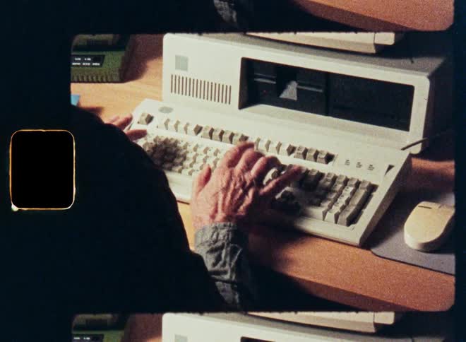 Hands of a man typing on a retro computer keyboard and using a mouse, shot on vintage film