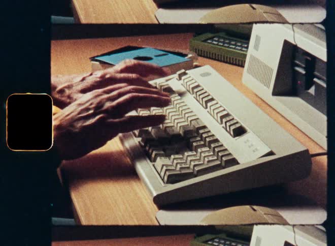Close-up of hands typing on a retro computer keyboard in a vintage film style