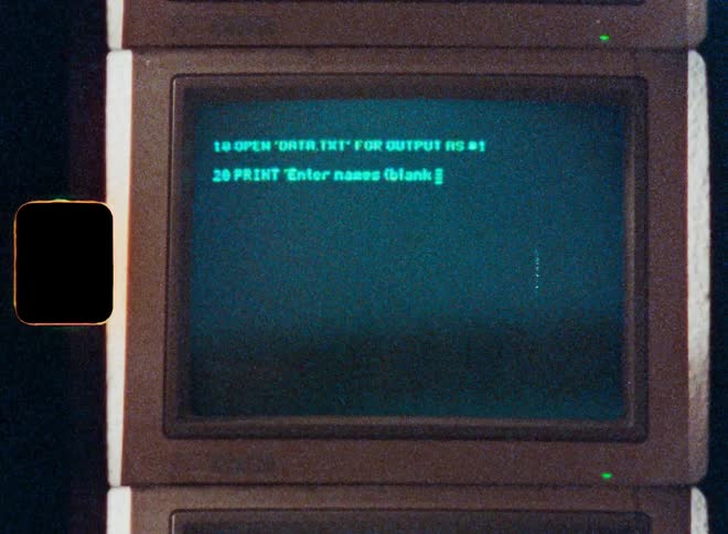 Close-up shot of a vintage computer screen with green text showing BASIC programming code being typed in