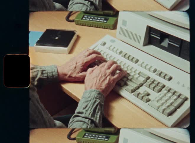 Vintage film shot shows a man typing on an old desktop computer from the 80s