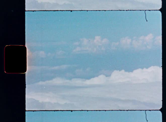 Authentic vintage film footage of a daytime sky with clouds and film grain