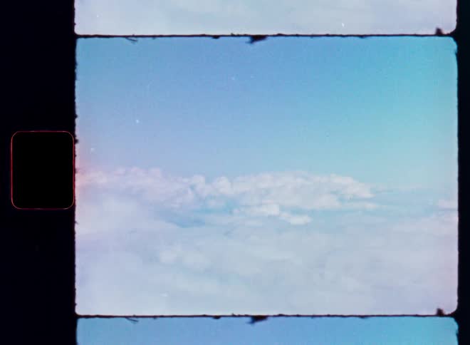A vintage 8mm film captures an aerial view of fluffy white clouds against a bright blue sky